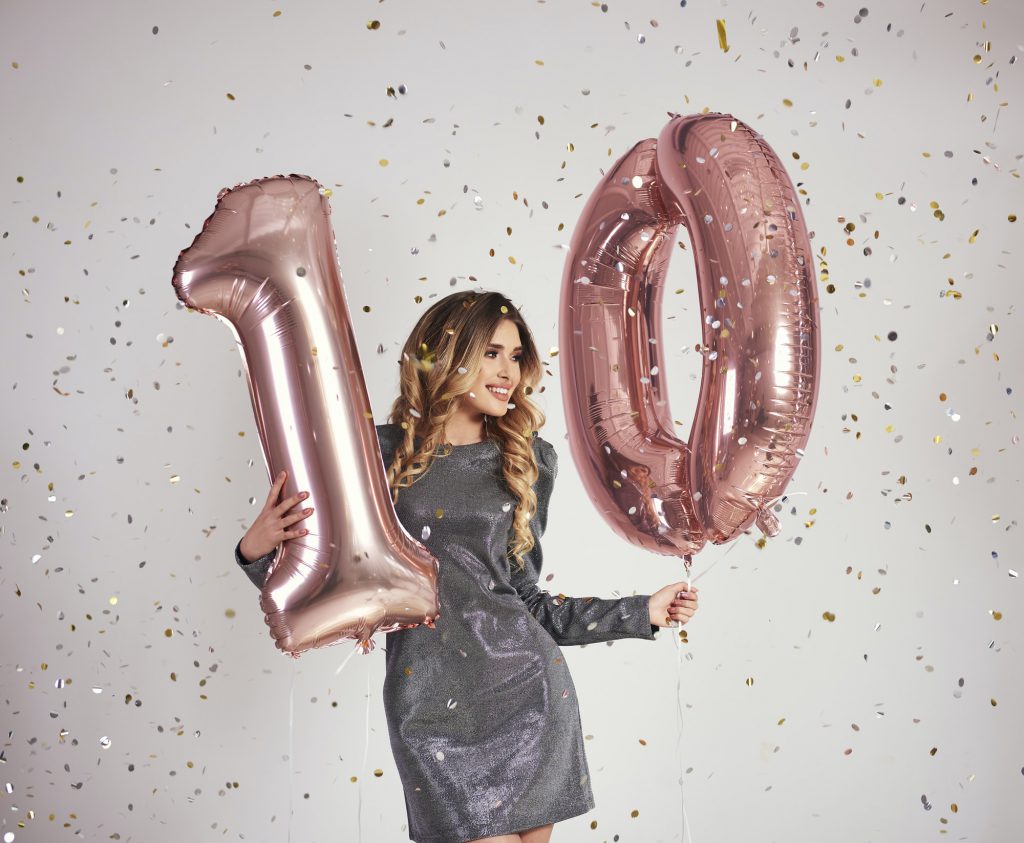 Young woman with balloons building the figure "10"
